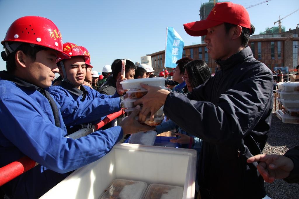 志愿者为参加技能大赛的建筑工人发放盒饭